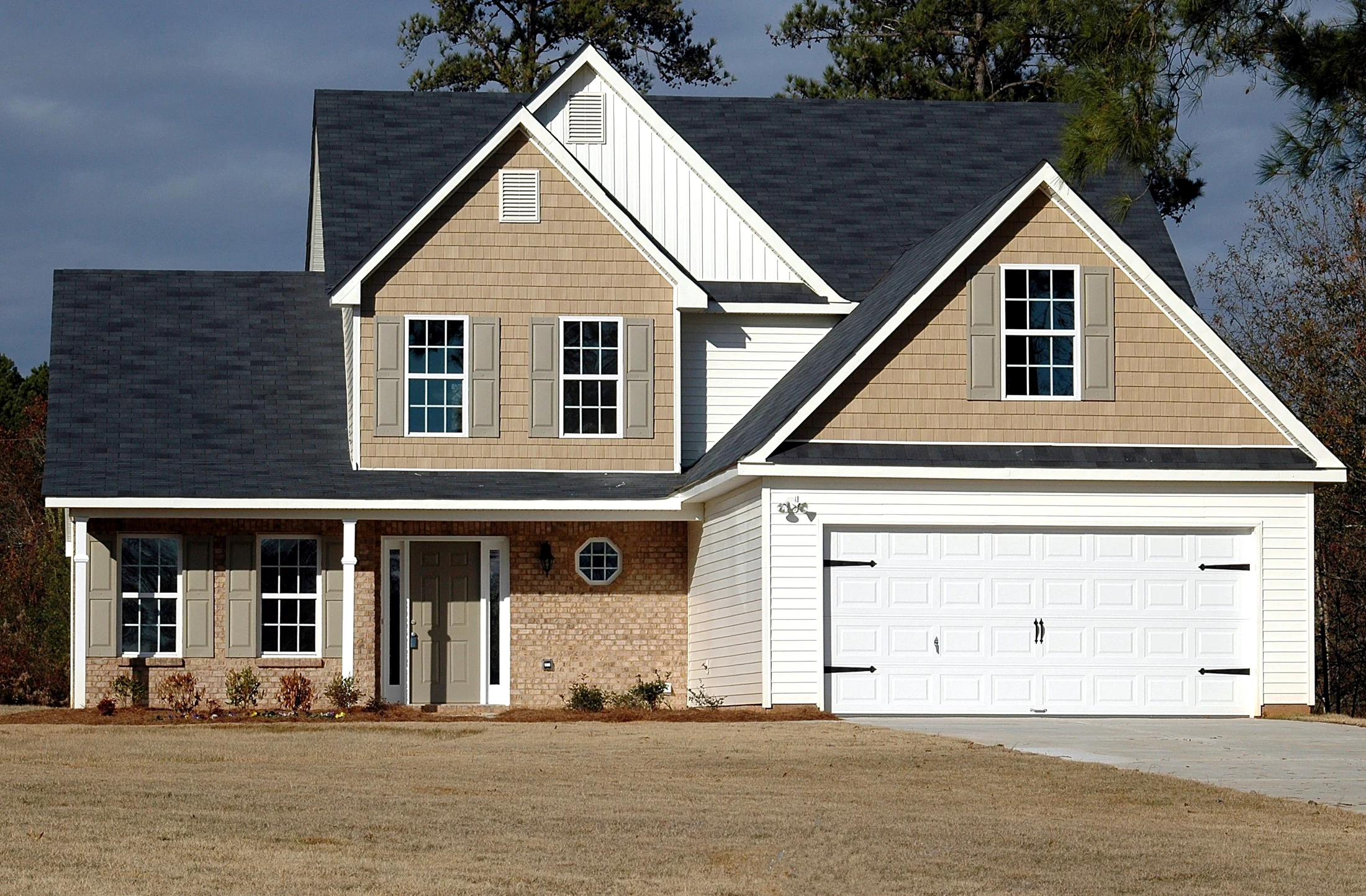 A light-colored home with a white double garage door